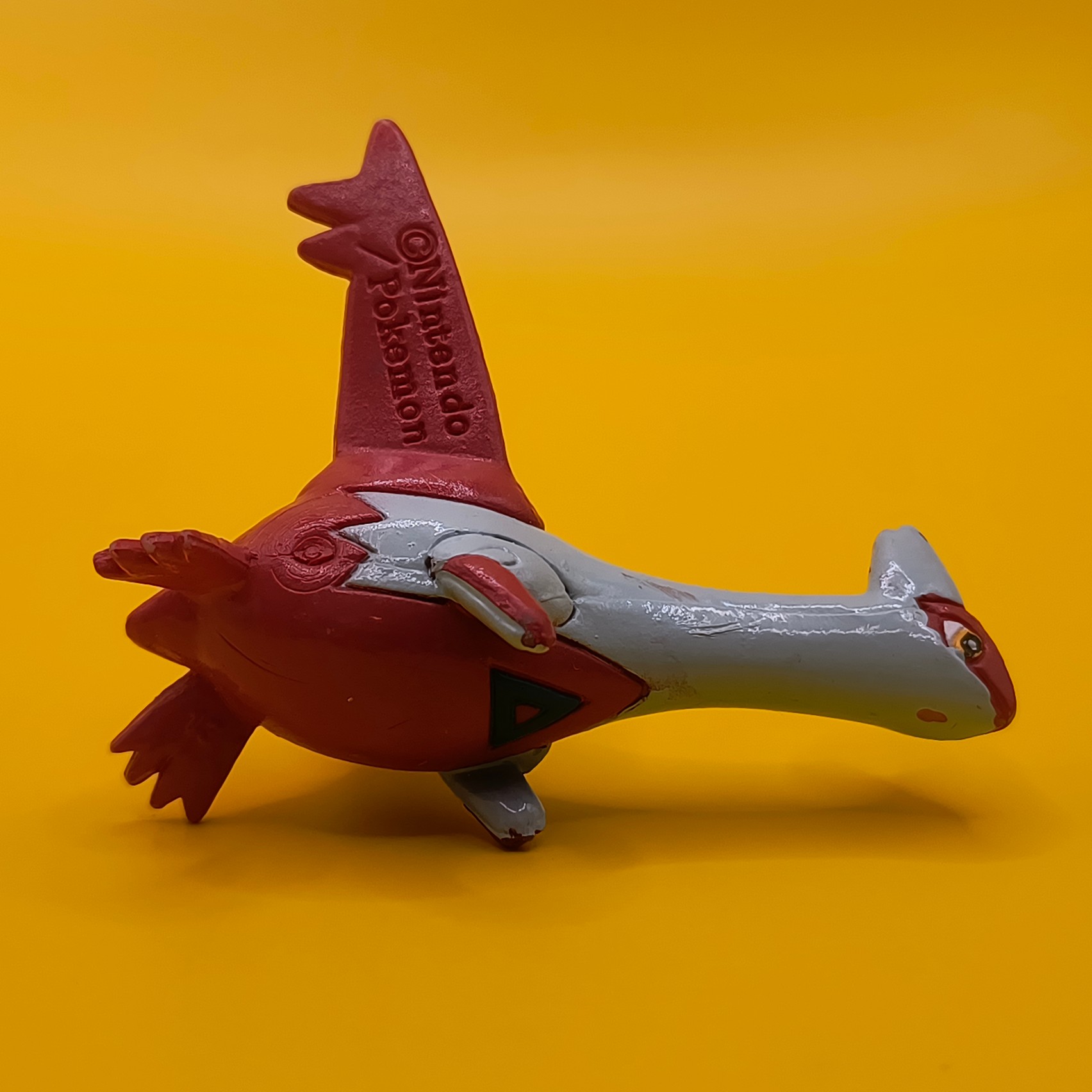 Rød og hvid Latias Pokémon-figur fra Bandai med stempler på vingerne.