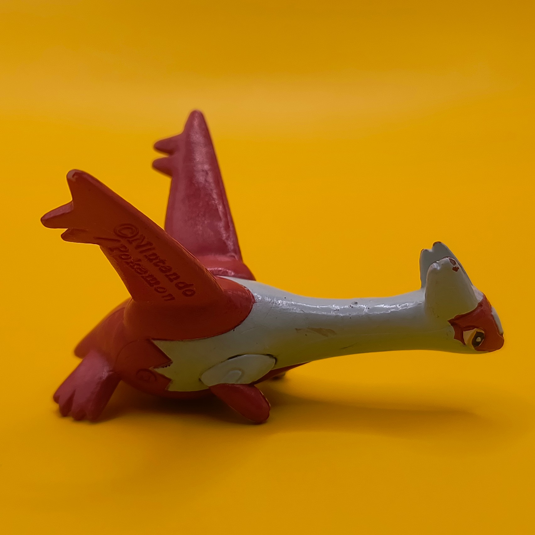 Rød og hvid Latias Pokémon-figur fra Bandai med stempler på vingerne.
